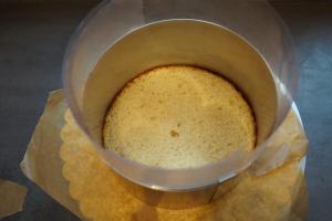 9) Den 1. Biskuit mit Buttercreme auf dem Cakeboard fixieren, Folie und Tortenring darum stellen