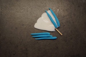 13) Zahnstocher einstechen und für jede Einkerbung blaue Linien formen und aufkleben
